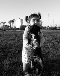 Portrait of girl playing with dog on field