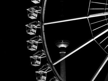 Low angle view of ferris wheel and fernsehturm tower at night