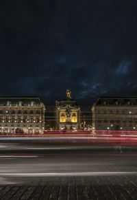 Light trails on street against buildings at night