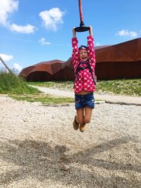 Full length of happy girl hanging on zip line