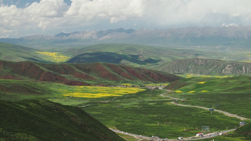 Scenic view of green landscape and mountains against sky