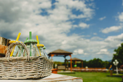 Close-up of wicker basket on field against sky