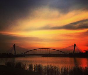 Bridge over river against cloudy sky