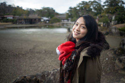 Portrait of smiling young woman wearing warm clothing standing outdoors