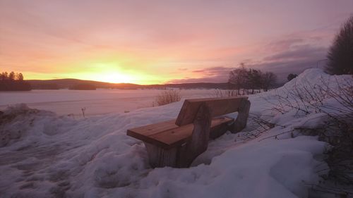 Scenic view of snow covered field against sky during sunset