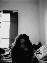 Woman sitting on bed at home