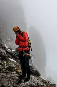 Full length of man standing on mountain during foggy weather