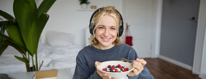 Portrait of young woman having food at home