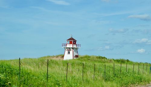 Lighthouse on field against sky