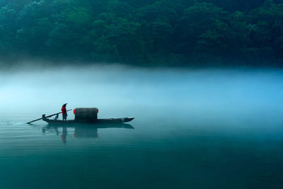 Man fishing in lake against sky