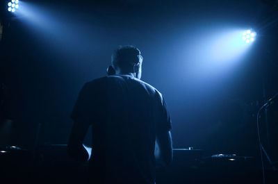 Rear view of dj performing at night