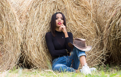 Portrait of young woman leaning on hay bale