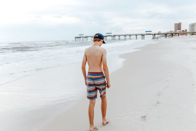 Full length of shirtless man standing on beach