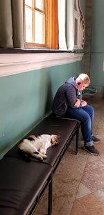 Man with dog sitting on window at home