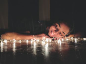 Portrait of girl lying down on table with fairy lights