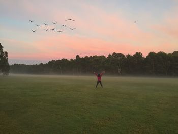 Man playing soccer on field against sky during sunset