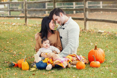 Family with pumpkins sitting on grassy land