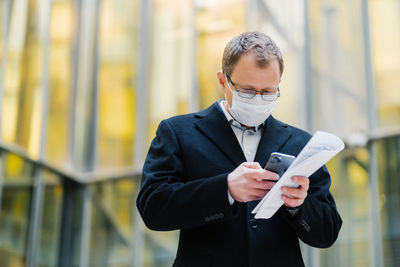 Businessman using smart phone while standing outdoors