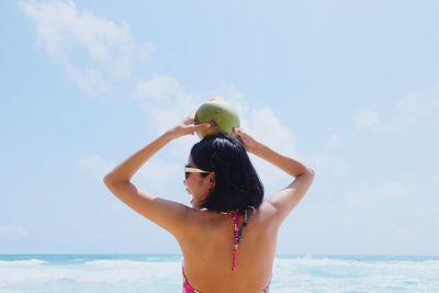 Woman standing at beach against sky