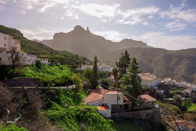 Houses by trees and mountains against sky