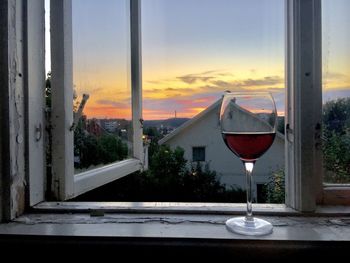 Close-up of wine glass on table against sky during sunset