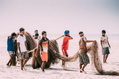 People standing on beach against clear sky