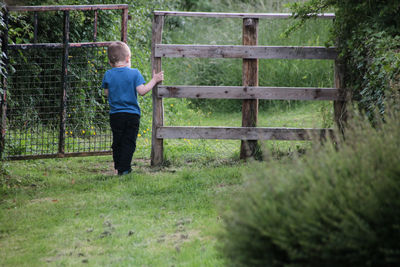 Rear view of boy standing by fence