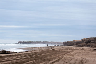 One person walking far away on a lonely beach