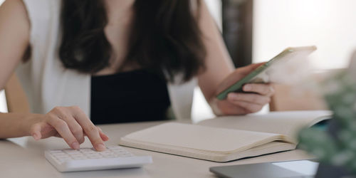 Midsection of woman using smart phone on table