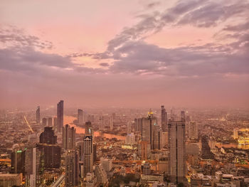 Aerial view of buildings in city against sky at sunset