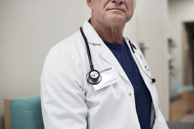 Midsection of man with arms raised standing against wall