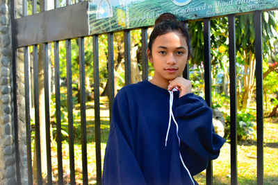 Portrait of teenage girl standing against gate
