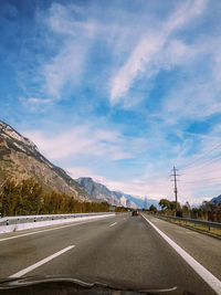 Road by mountains against sky