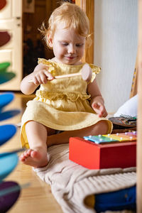 Cute baby girl sitting on floor at home