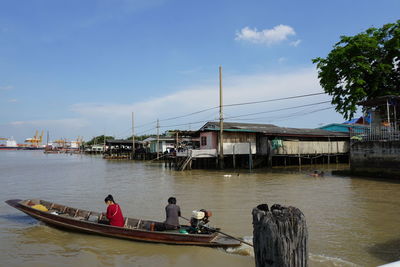 People on boat in river against sky