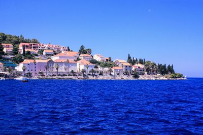 Townscape by sea against clear blue sky