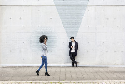 Side view of people walking on concrete wall