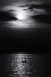 Silhouette fisherman in sea against sky