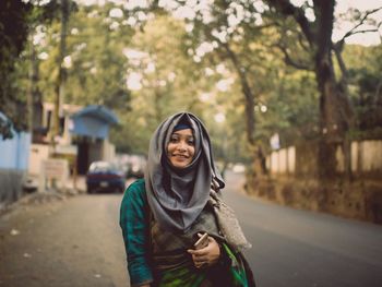 Portrait of smiling young woman against trees