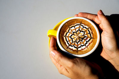 Cropped image of hand holding coffee cup against gray background