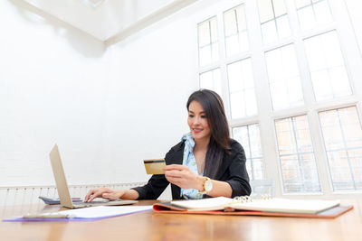Young woman using mobile phone while sitting on table