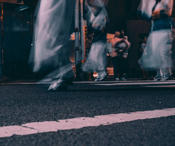 Low section of people walking on road in city