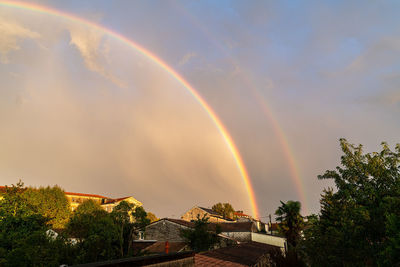 Low angle view of rainbow over buildings against sky