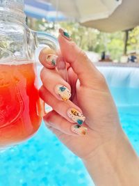 Close-up of hand holding glass at swimming pool