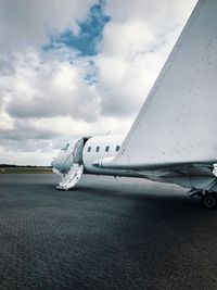 Airplane at airport runway against sky