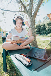 Young woman using laptop while sitting on field