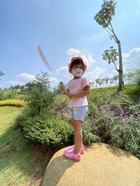 Full length of girl standing by plants against sky