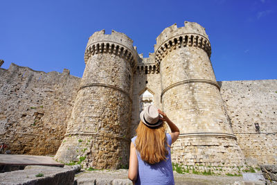 Tourist girl walking down the marine gate main entrance to rhodes town from the harbour, greece