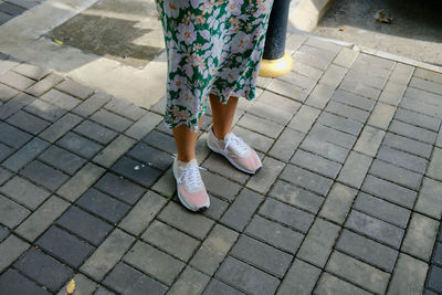 Low section of woman standing on footpath