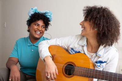 Smiling young woman playing guitar